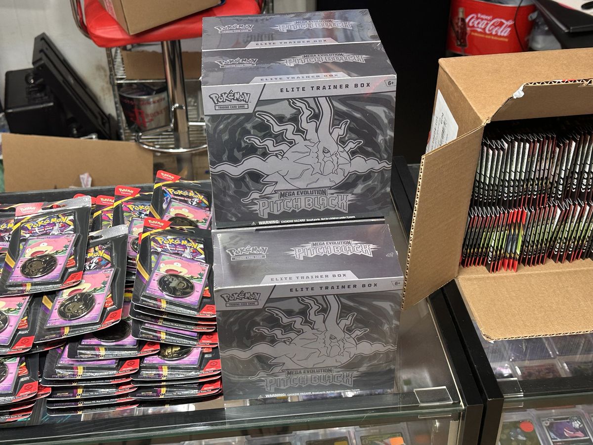 Sealed Pokémon Mega Evolution Pitch Black Elite Trainer Boxes and blister packs on the counter